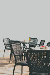 Wicker chairs by the empty outdoor restaurant tables
