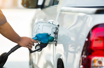 Hand refilling the white pickup truck with fuel at the gas station