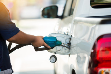 Hand refilling the white pickup truck with fuel at the gas station
