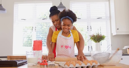Front view of black mother and daughter baking cookies in kitchen at home 4k - Powered by Adobe