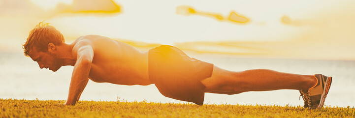Fitness man working out arms doing push-ups outside in sunset. Fit body male athlete workout outdoor full length panoramic banner.