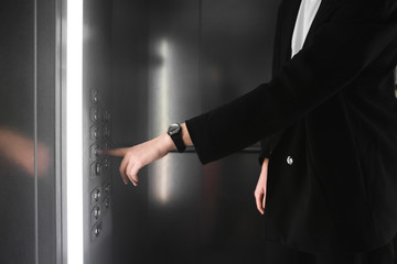 Woman pressing the button in the elevator. Businesswoman in the smart suit presses the button of...