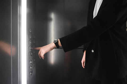 Woman pressing the button in the elevator. Businesswoman in the smart suit presses the button of the lift. Close-up photo.