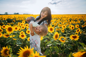 Mom and son are playing in the field of sunflowers