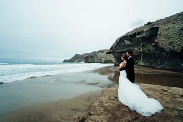 The bride and groom are walking along the beach. Panoramic view.