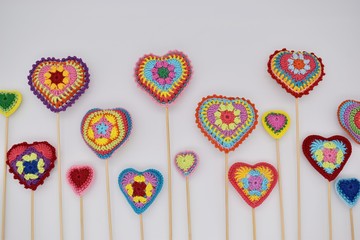 Knitted hearts on wooden sticks on a white background. Valentine's Day, handmade.