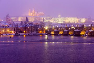 Fototapeta na wymiar Foggy night Prague Lesser Town with gothic Castle, Bridge Tower and St. Nicholas' Cathedral in the Snowstorm, Czech republic
