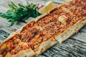 Traditional Turkish Pide or Pita pastry product on wooden table in turkish restaurant.