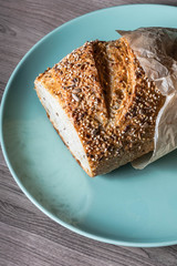 Loaf of cereal bread in a blue plate on a wooden table