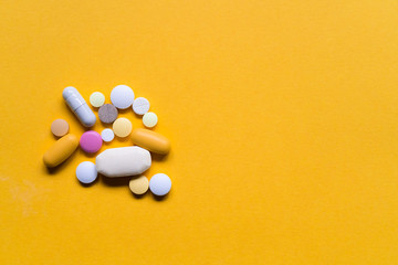 Colorful pills and drugs isolated on yellow background. Various kinds of medicine.