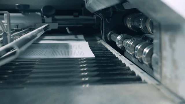 Printed sheets moving on a special conveyor, close up.