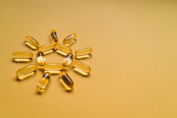 Close up capsules of fish fat oil in the sun shape, omega 3, vitamin e isolated on yellow...