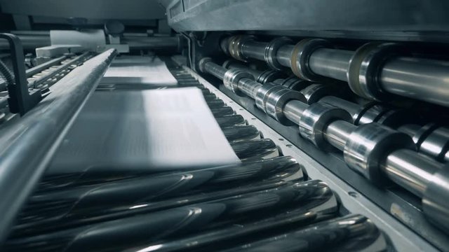 Machine prints paper at a factory, close up.