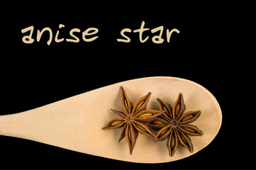 anise star on wooden spoon isolated on black background. Latin name Illicium verum.