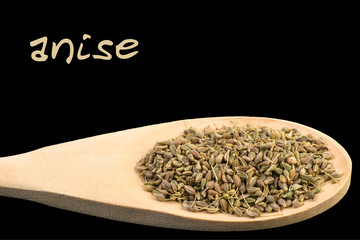 anise on wooden spoon isolated on black background. Latin name Pimpinella