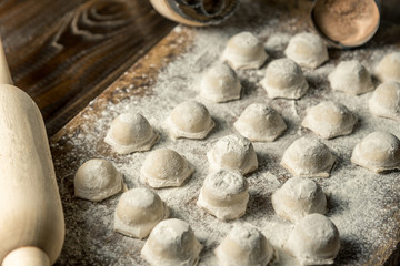 Uzbek national food Chuchvara, like dumplings, with a rolling pin, on a wooden board, in flour