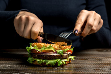 Healthy lifestyle, proper nutrition. Female hands cut a useful rice burger with vegetables, herbs and cutlet on a wooden board