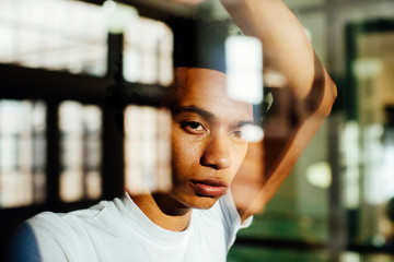 Portrait of a young man standing by the window and looking out with no expression