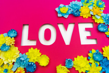 Inscription Love cut out of paper. Pink background. Flower made of paper.