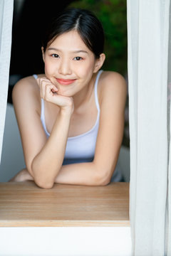 beautiful asian teen  white Tank top happiness smile enjoy freshness morning with near window with sun light