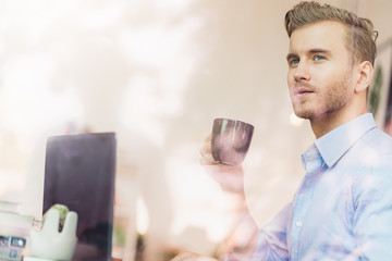 smart handsome caucasian businessman freelance working with laptop and enjoy coffee by big window in coffee shop