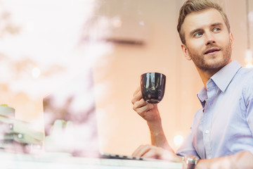 smart handsome caucasian businessman freelance working with laptop and enjoy coffee by big window in coffee shop