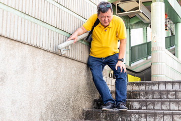 Man with painful knee struggle walking down flight of stairs