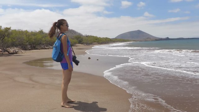 Galapagos tourist walking on travel on Espumilla Beach, Santiago Island, Galapagos Islands, Ecuador.