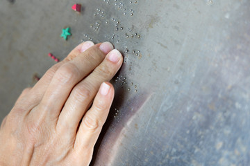 Finger reading braille tactile on public park message board