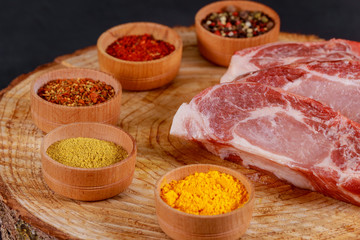 Fresh steak and aromatic herbs, spices and vegetables on wood background, top view