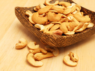 Dry roast Cashew nut in wood bowl on wood table and space for write wording, delicious snack and ingredient for making food, cookie, cake, served with coffee or tea for special celebration or party