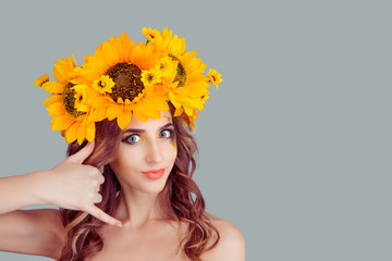 Picture of beautiful woman in floral crown from sunflowers making a call me gesture