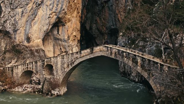 Aerial, man sits on bridge in Pindus