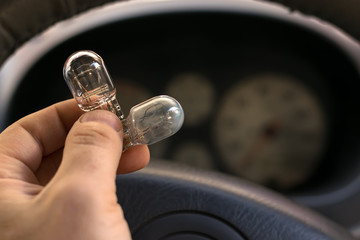 new and burnt out car light bulb, in man's hand