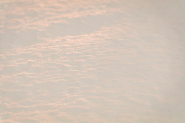 Snow at sunrise reflects a coral tone for winter background