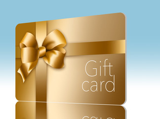 A gold gift card with a gold bow and ribbon is pictured here isolated on the background.
