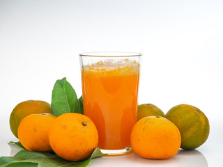 Glass with orange juice and fruits with green leaves