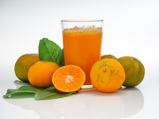 Glass with orange juice and fruits with green leaves