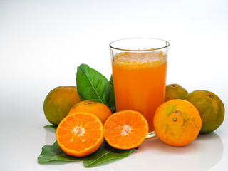 Glass with orange juice and fruits with green leaves