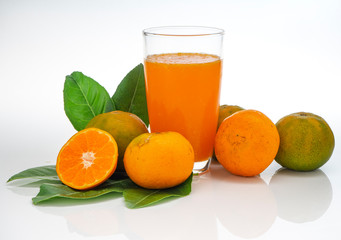 Glass with orange juice and fruits with green leaves