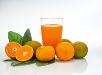 Glass with orange juice and fruits with green leaves