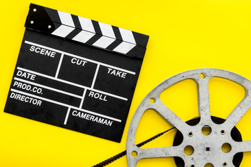 Filmings concept. Clapperboard and film stock on yellow background top view space for text
