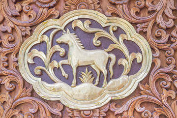 Traditional Thai style wood carving horse of 12 Zodiac,on the wall of temple in Thailand