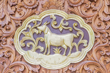 Traditional Thai style wood carving Goat of 12 Zodiac,on the wall of temple in Thailand