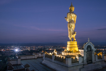 An iconic standing Buddha on Wat Phra That Khao Noi one of the most tourist attraction places in Nan province of northern Thailand. Night view of Nan province.