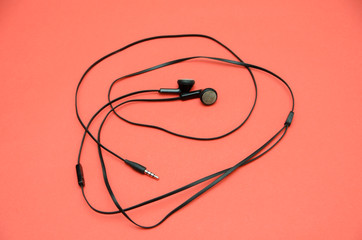 Beautiful modern, digital, plastic, vacuum, black headphones with wires for listening to music on a purple-pink background