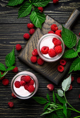 Raspberry smoothie in glass jars with fresh berry and yogurt on vintage wooden kitchen table background, flat lay, top view