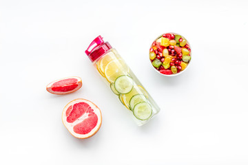 Fototapeta na wymiar Weight loss concept. Fruit salad near fruit lemon and cucumber water on white background top view