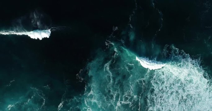 Top down aerial view of giant ocean waves crashing and foaming