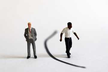 A miniature white man and a miniature black man standing between the boundaries.